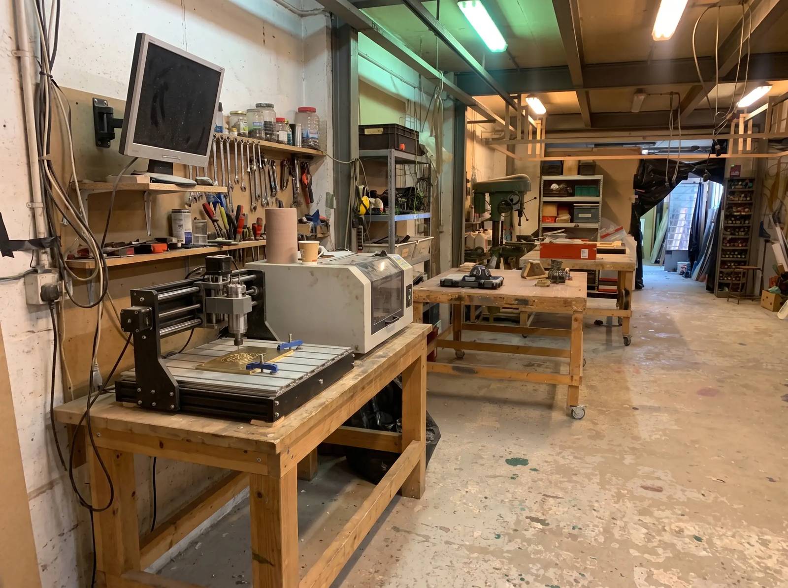 A wide view of the workshop: the milling machine in the foreground, workbenches and the drill press behind