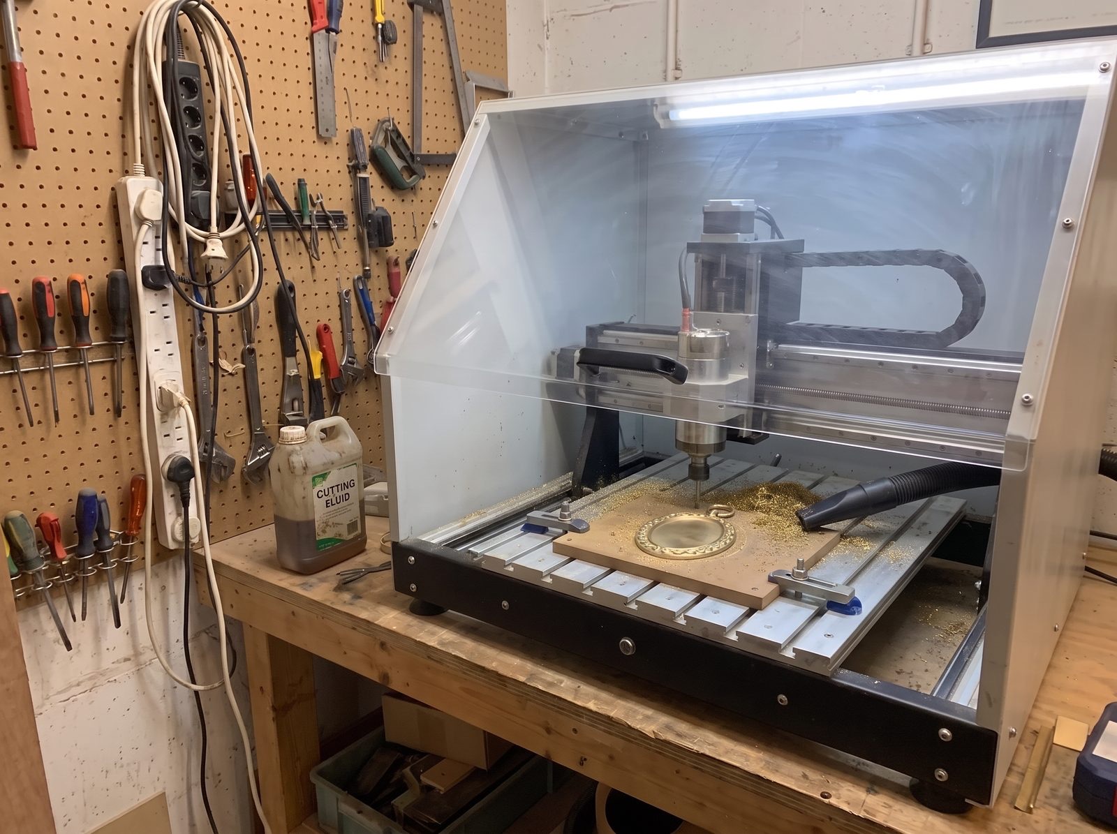 A medallion being engraved under the machine hood